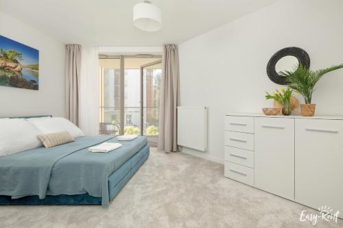 a white bedroom with a bed and a dresser at Apartamenty Pinea z widokiem na morze Easy - Rent Apartments in Pobierowo