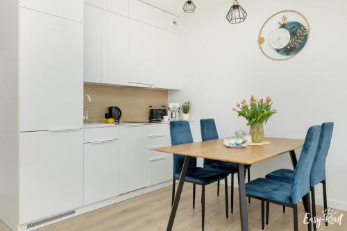 a kitchen with a wooden table and blue chairs at Apartamenty Pinea z widokiem na morze Easy - Rent Apartments in Pobierowo