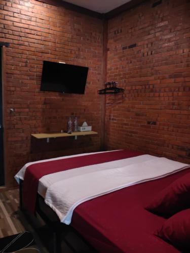 a bedroom with a bed and a tv on a brick wall at GRHA PAWITRA TROWULAN in Trowulan