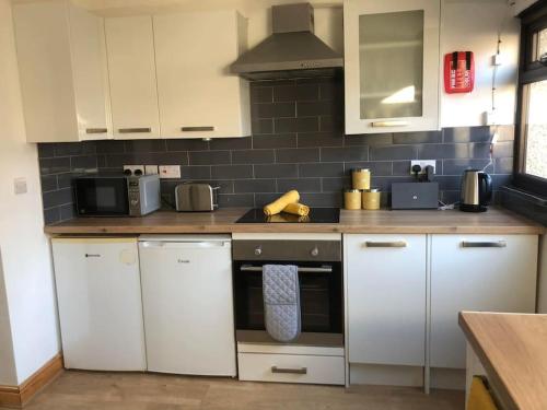 a kitchen with white cabinets and a stove top oven at Cheerful 3 Bedroom Townhouse in Bangor