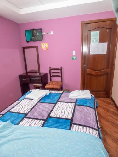 a bedroom with two beds with purple walls at Hotel El Ejido in Quito