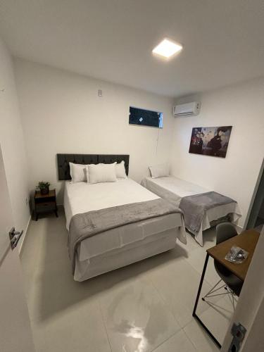 a bedroom with two beds and a table and a desk at Torre Hotel in Jaguaquara