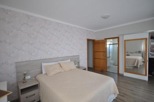 a bedroom with a white bed and a bathroom at Casa agradável a 03 minutos do centro in Poços de Caldas