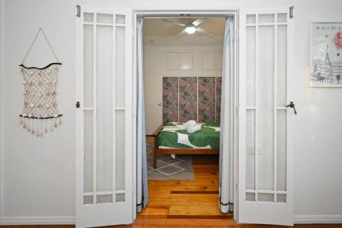 a door leading to a bedroom with a bed at Groovy Beach Bungalow in Caloundra