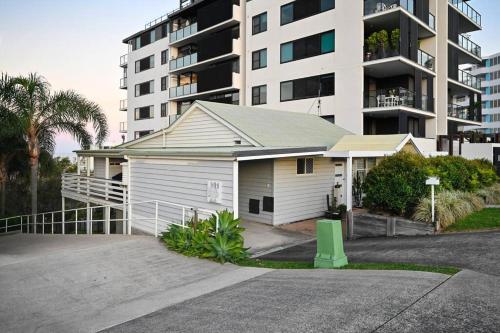 a house with a garage in front of a building at Groovy Beach Bungalow in Caloundra
