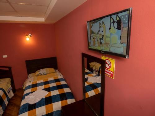 a room with two beds and a tv on the wall at Hotel El Ejido in Quito
