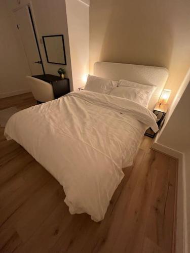 a white bed in a room with a wooden floor at Whole House Modern Two Bedroom in Newcastle - Free Parking in Newcastle upon Tyne
