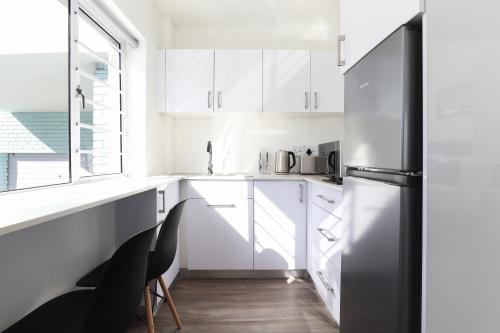 a kitchen with white cabinets and a refrigerator at Modern & stylish apartment in Cape Town