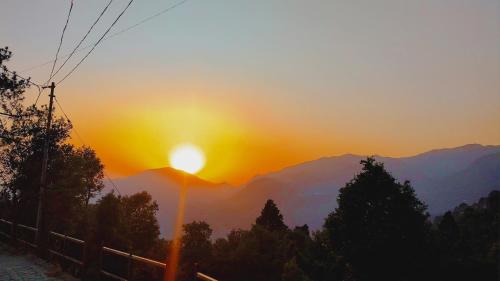a sunset in the mountains with a street light at Camp Gopika in Patwa Dunga