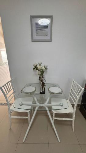 a glass table with two chairs and a vase with flowers at Ecusuites Jacuzzi en Playas Vista Mar in Playas