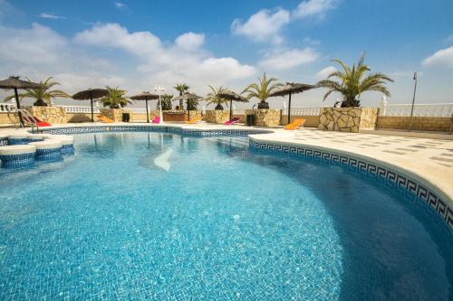 a large swimming pool with blue water and palm trees at Hotel Costa Blanca Rojales in Rojales