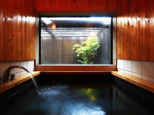 a bathroom with a window and a tub with water at 旗籠白忠 in Nagahama
