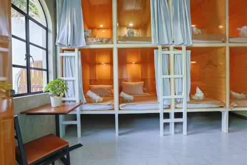 a room with bunk beds with a table and a chair at Tahan Hostel in Puerto Princesa City