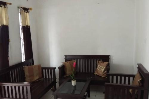 a room with two benches and a table with a flower on it at homestay Icut syariah in Sambong-hilir