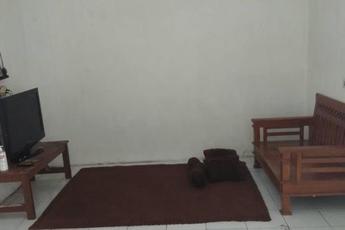 a living room with a tv and a brown rug at homestay Icut syariah in Sambong-hilir