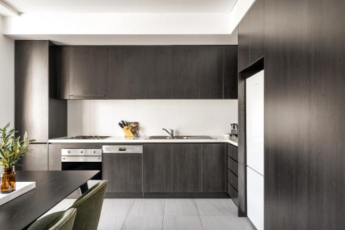 a kitchen with dark wood cabinets and a table at Pyrmont Apartments by Urban Rest in Sydney