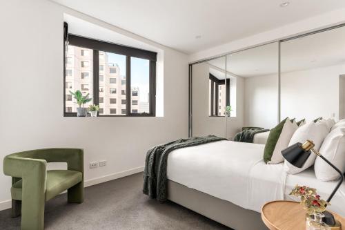 a bedroom with a large bed and a green chair at Pyrmont Apartments by Urban Rest in Sydney