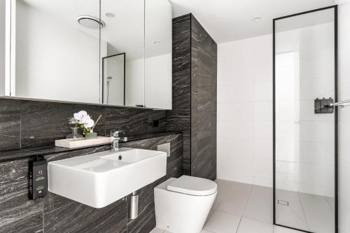 a bathroom with a white sink and a toilet at Pyrmont Apartments by Urban Rest in Sydney