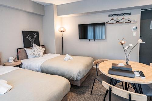 a hotel room with two beds and a table at Apartment Hotel 11 Umeda Kamiyama in Osaka