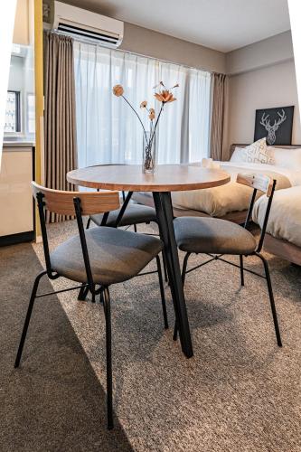 a room with a table and two chairs and a bed at Apartment Hotel 11 Umeda Kamiyama in Osaka