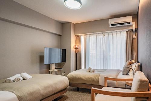 a hotel room with two beds and a flat screen tv at Apartment Hotel 11 Umeda Kamiyama in Osaka