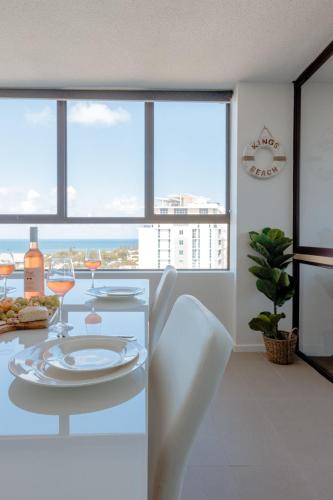 a dining room with a table with wine glasses at Breezy Kings Beach Apartment with Ocean Views in Caloundra