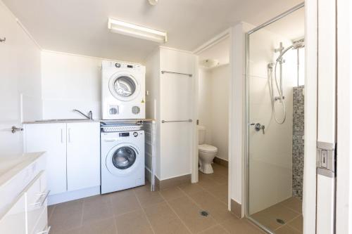 a bathroom with a washing machine and a washer at Breezy Kings Beach Apartment with Ocean Views in Caloundra