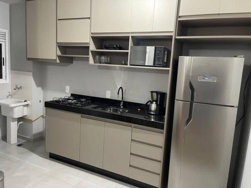 una cocina con frigorífico y fregadero en Aconchego Familiar, en Londrina