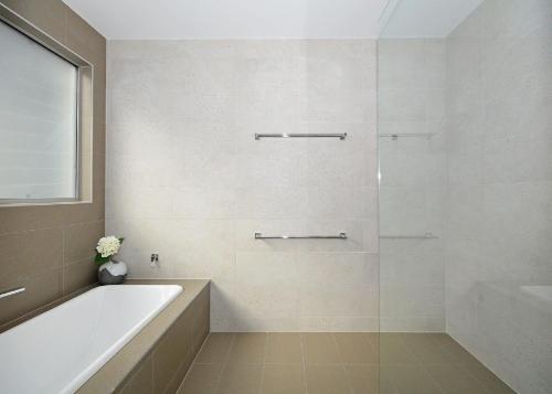 a white bathroom with a tub and a sink at Beachside - Burrum Heads- Beachfront - 3BR- Wifi in Burrum Heads