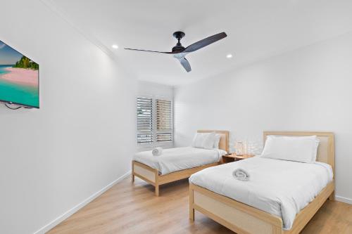 a bedroom with two beds and a ceiling fan at Serenity Apartments Noosa in Noosa Heads