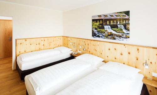 two beds in a room with wooden walls at Pension Jageredt in Nussbach