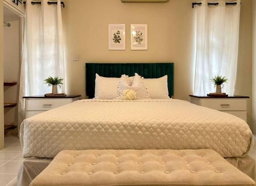 a large bed in a bedroom with two windows at Falcon Sunset 2br- Airport Transport Available -Security-Gated in Montego Bay