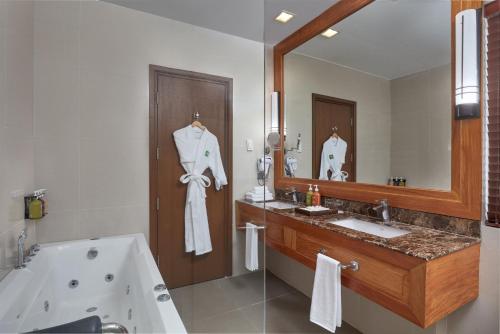 a bathroom with a tub and a sink and a mirror at Holiday Inn & Suites Batangas LimaPark by IHG in Batangas City