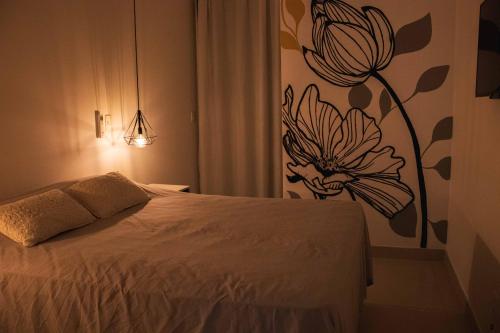 1 dormitorio con 1 cama con una flor en la pared en Apartamento Resort em Praia grande - Ubatuba, en Ubatuba