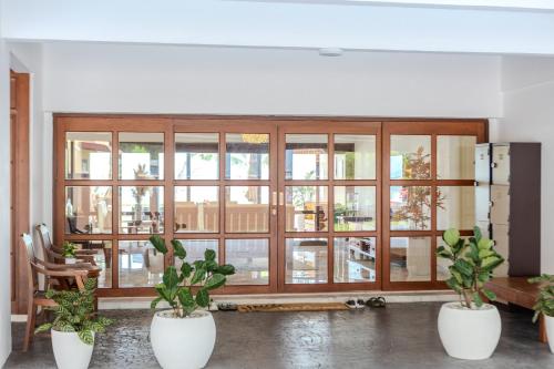 a room with three potted plants in front of a large window at Suntai Villa, Beachfront Suites in Kampong Si Ginting