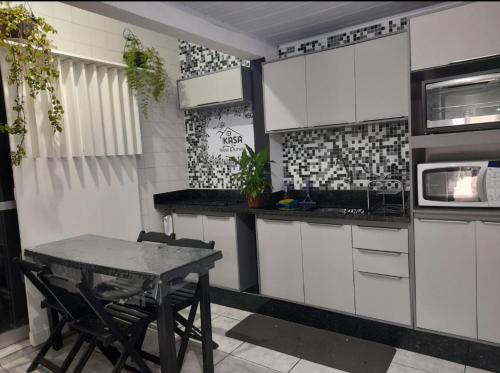 a kitchen with white cabinets and a table with chairs at Kasa Hostel Karaokê in Balneário Camboriú