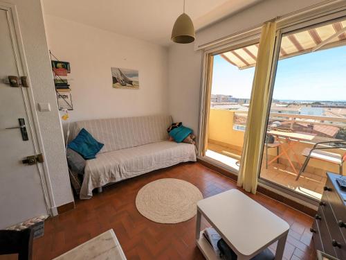un salon avec un canapé et une grande fenêtre dans l'établissement Charmant T2 traversant, plage à 100m, balcon, bien équipé, idéal 4 personnes - FR-1-797-3, à Port-la-Nouvelle