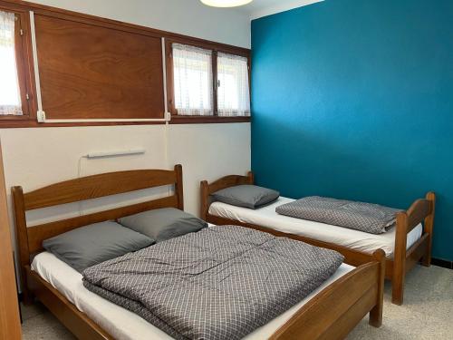 Cette chambre comprend 2 lits et un mur bleu. dans l'établissement T2 Climatise en RDC Face Mer 5 Pers PKG - FR-1-797-7, à Port-la-Nouvelle