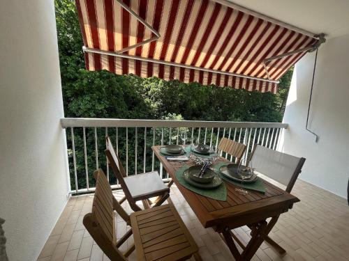 - une table et des chaises en bois sur un balcon avec un parasol dans l'établissement Studio Cabine avec Balcon Sud, Parking Privé à Arcachon - FR-1-374-227, à Arcachon