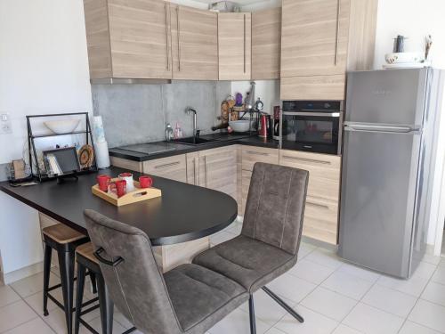 une cuisine avec une table, des chaises et un réfrigérateur dans l'établissement T3 Climatisé RDC avec Terrasse, Parking, Proche Activités - Port-la-Nouvelle - FR-1-797-30, à Port-la-Nouvelle