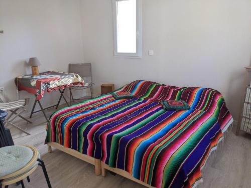 - une chambre avec un lit et une couverture rayée colorée dans l'établissement T3 Climatisé RDC avec Terrasse, Parking, Proche Activités - Port-la-Nouvelle - FR-1-797-30, à Port-la-Nouvelle