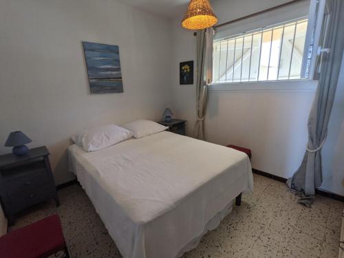 une chambre avec un lit blanc et une fenêtre dans l'établissement T2 Climatisé 4 pers. avec Parking, Front de mer, Port-la-Nouvelle - FR-1-797-10, à Port-la-Nouvelle