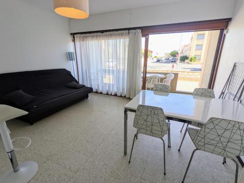 un salon avec un canapé, une table et des chaises dans l'établissement T2 climatisé en front de mer avec parking - FR-1-797-13, à Port-la-Nouvelle