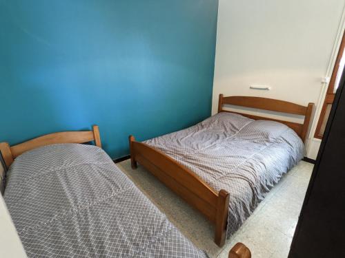 une chambre avec deux lits et un mur bleu dans l'établissement T2 climatisé en front de mer avec parking - FR-1-797-13, à Port-la-Nouvelle