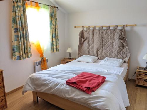 une chambre avec un lit avec une serviette rouge dessus dans l'établissement Belle villa climatisée T3 avec mezzanine, jardin arboré, garage et à 900m de la plage, 6/7 personnes - FR-1-797-36, à Port-la-Nouvelle