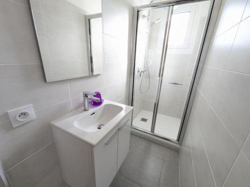 une salle de bain blanche avec un lavabo et une douche dans l'établissement Agréable T2, 4 pers, plain-pied ouvert sur terrasse, jardin clos, parking privé, proche plage et commerces - FR-1-797-24, à Port-la-Nouvelle