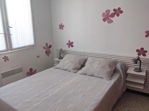 - une chambre avec un lit orné de fleurs roses sur le mur dans l'établissement Charmant T3 rénové à 60m de la plage avec terrasse, jardin et parking clos - FR-1-797-28, à Port-la-Nouvelle