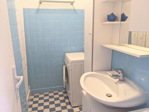 La salle de bains est pourvue d'un lavabo, de toilettes et de carrelage bleu. dans l'établissement Charmant T3 rénové à 60m de la plage avec terrasse, jardin et parking clos - FR-1-797-28, à Port-la-Nouvelle