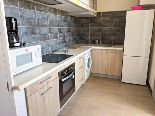Il comprend une cuisine équipée d'un réfrigérateur blanc et d'une cuisinière. four supérieur dans l'établissement Charmant T4 climatisé pour 6 pers, proche plage, jardin, parking, terrasse, tout équipé - FR-1-797-25, à Port-la-Nouvelle