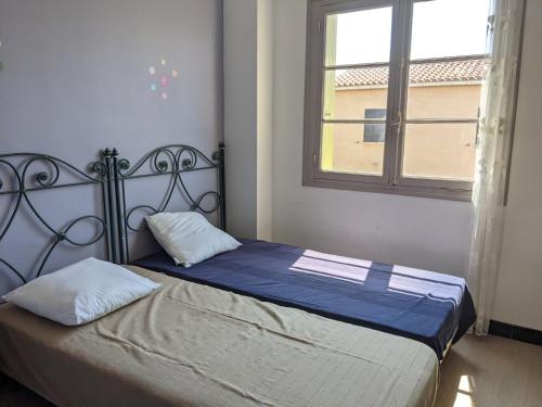 une chambre avec un lit avec des draps bleus et une fenêtre dans l'établissement Charmant T4 climatisé pour 6 pers, proche plage, jardin, parking, terrasse, tout équipé - FR-1-797-25, à Port-la-Nouvelle